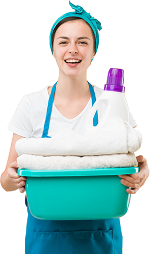 A young woman in a blue apron is holding a green tub with clean linen and a bottle of washing detergent in it.